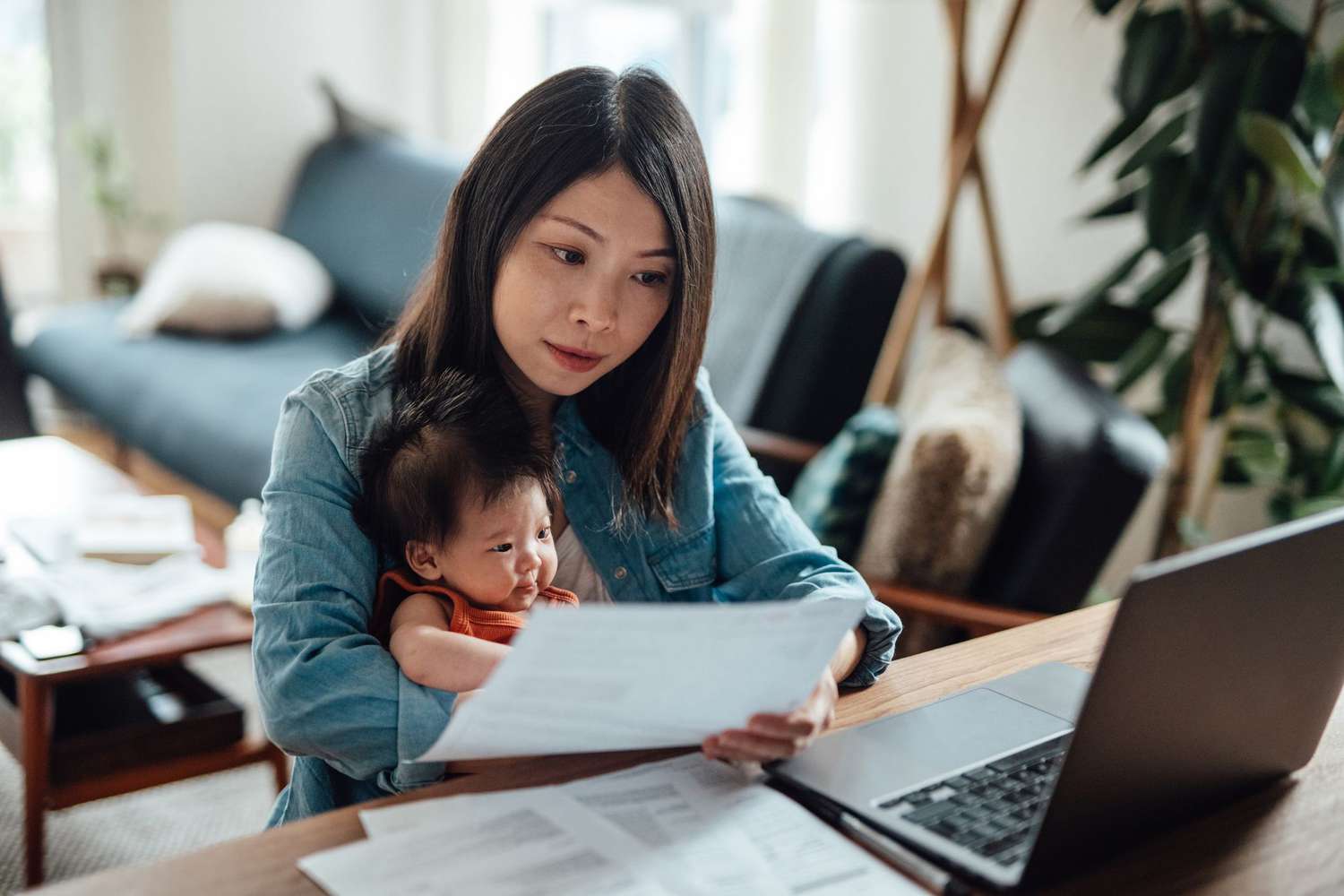 Woman with baby and computer looking at papers