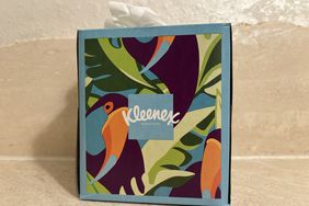 A blue, green, and orange Kleenex box sits on a counter.