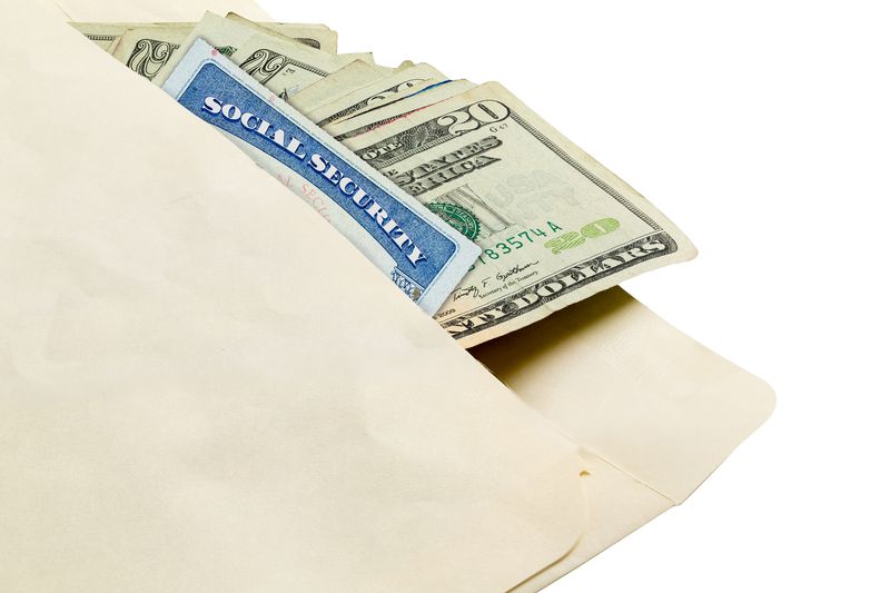 A social security card and twenty dollar bills in envelope against white background.