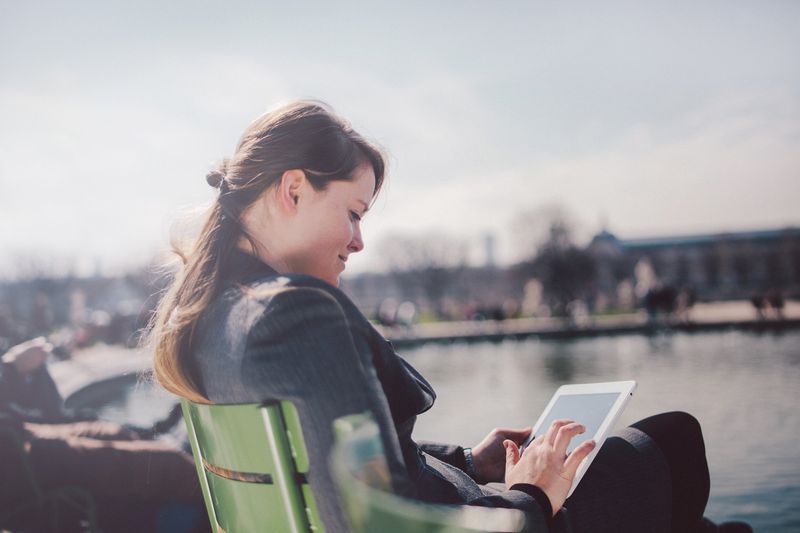 Person with tablet on bench.