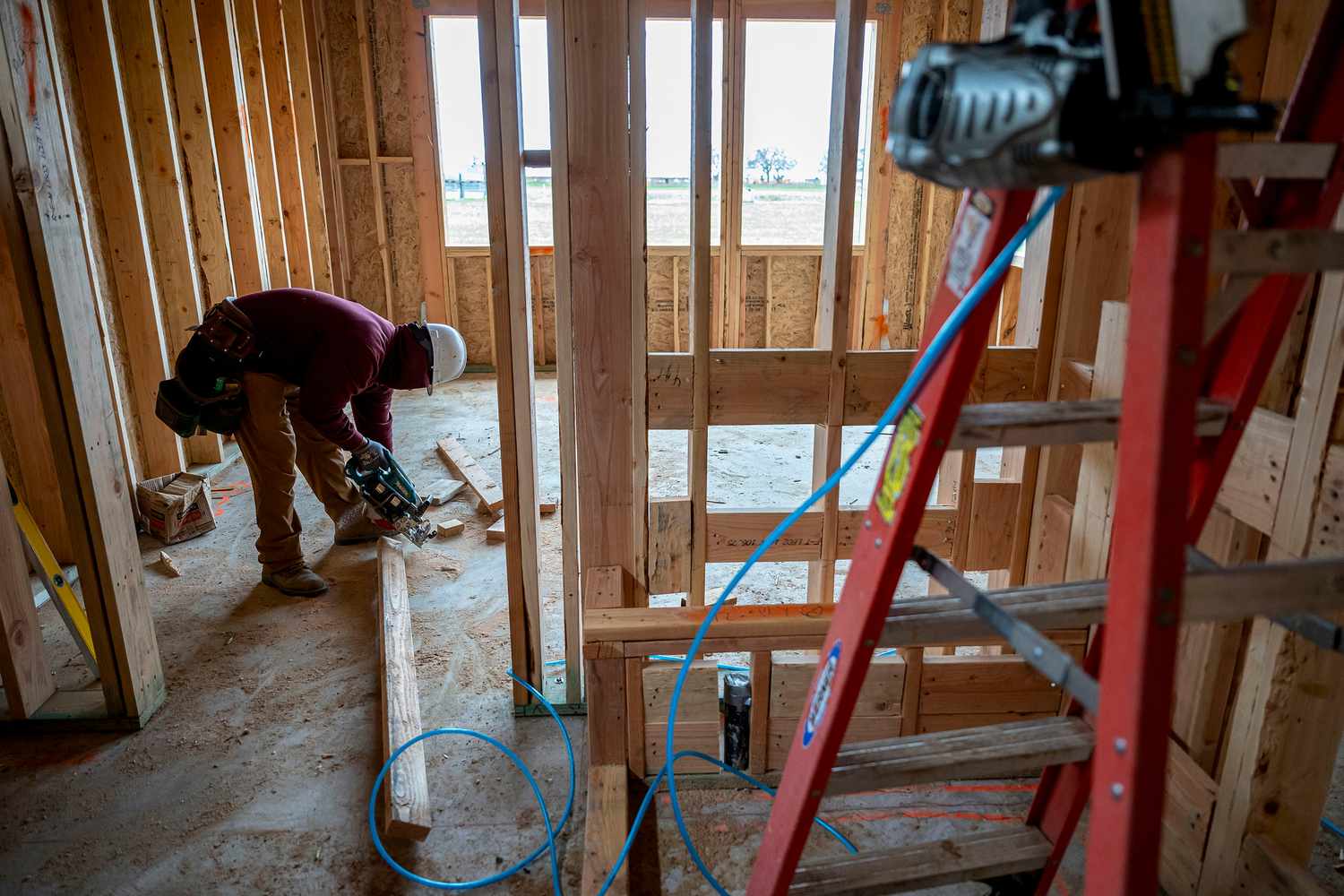 A contractor cuts wood inside a house under construction at the Toll Brothers Redwood, a 55 years of age and up active adult community, in Folsom, California, US, on Thursday, March 6, 2025.