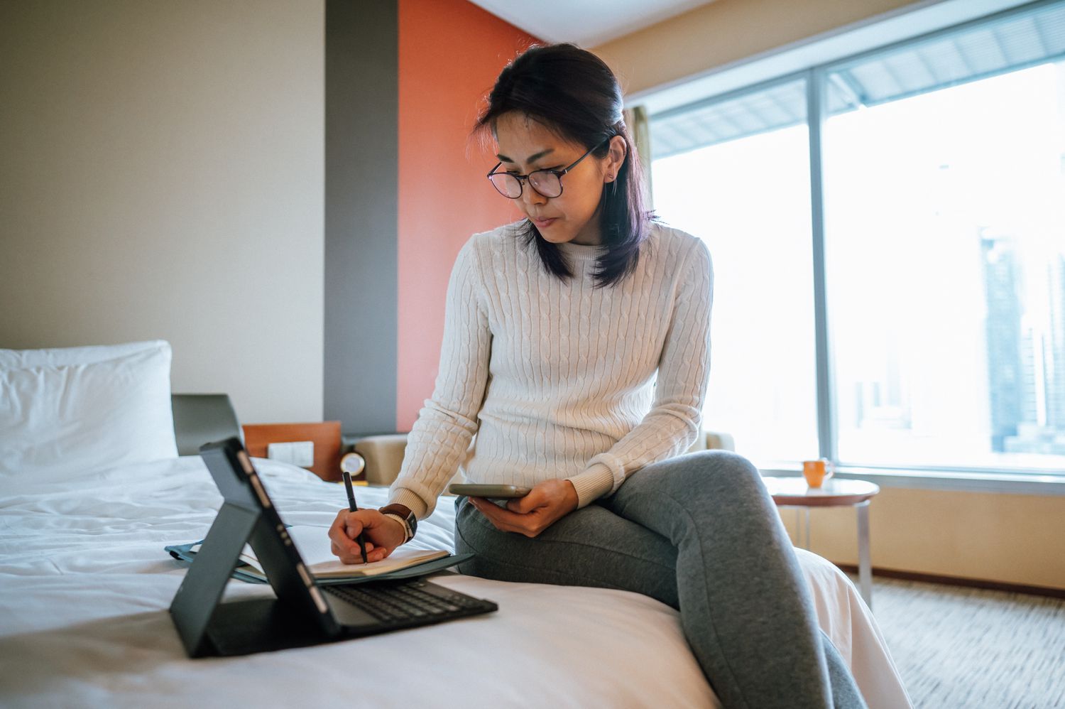 Woman researching what a deferment period is on a hotel bed