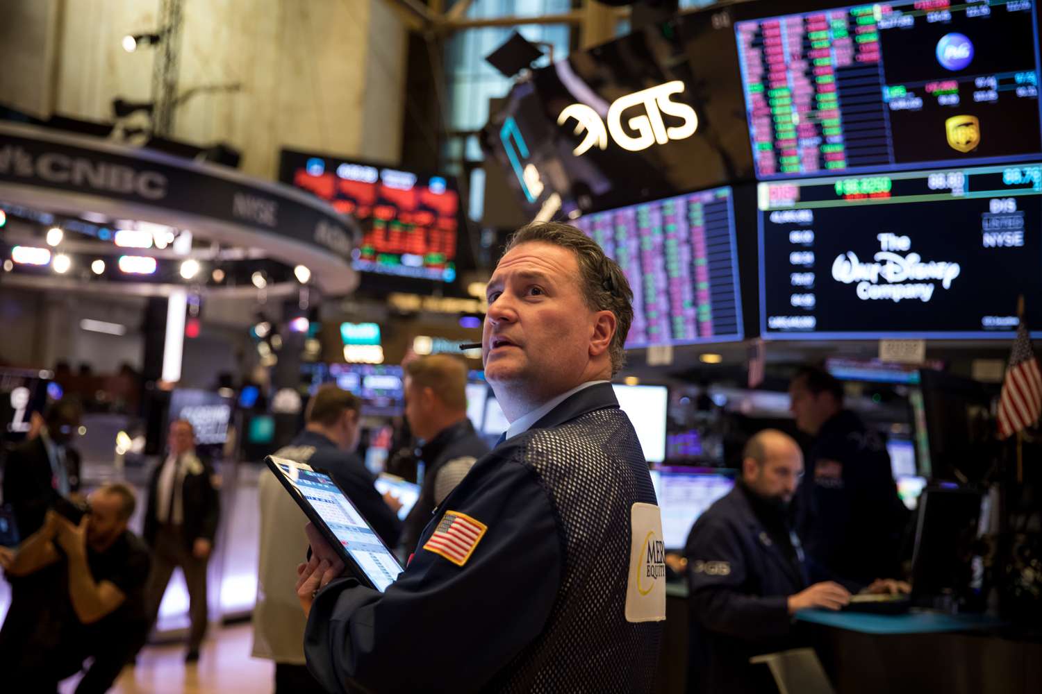 A trader looks over his shoulder while holding a tablet on the floor of the New York Stock Exchange