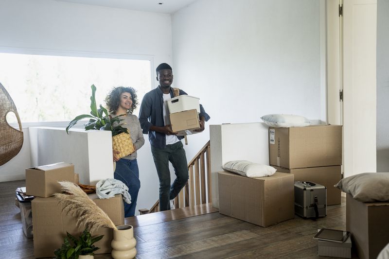 Two people with moving boxes in a house