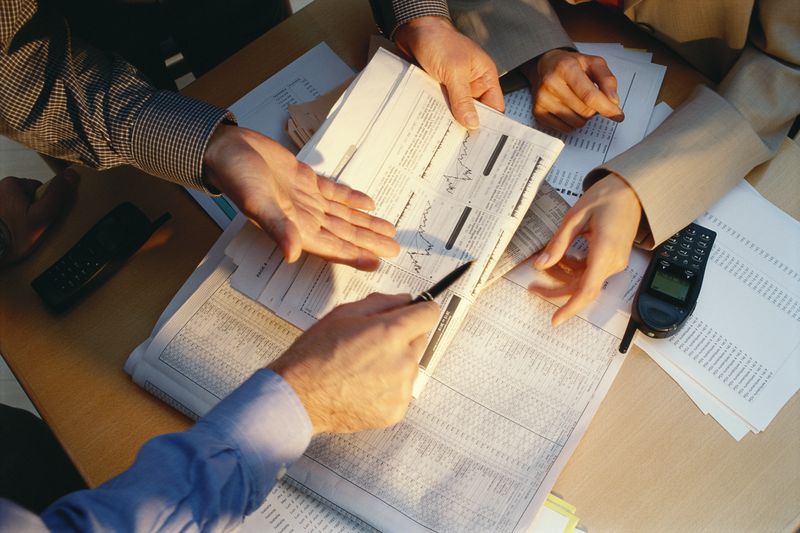 A group of business people holding and discussing paperwork