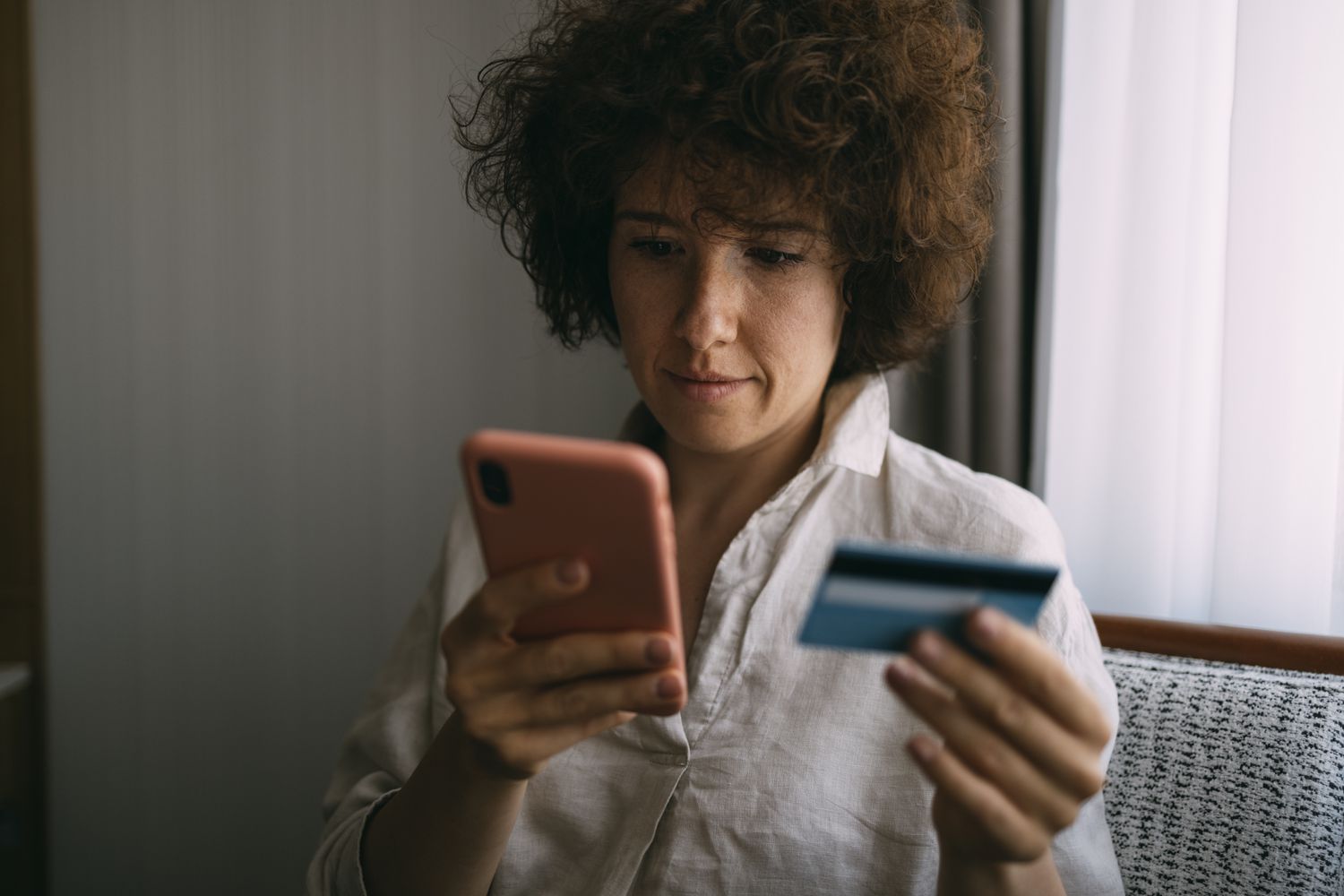 Young adult looking up information about whether or not applying for a new credit card can hurt credit score on the phone.