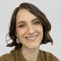 A photograph shows writer Elyssa Kirkham. She's smiling and poses in front of a textured, off-white background.