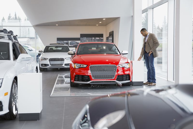 Man looking at car in car dealership showroom