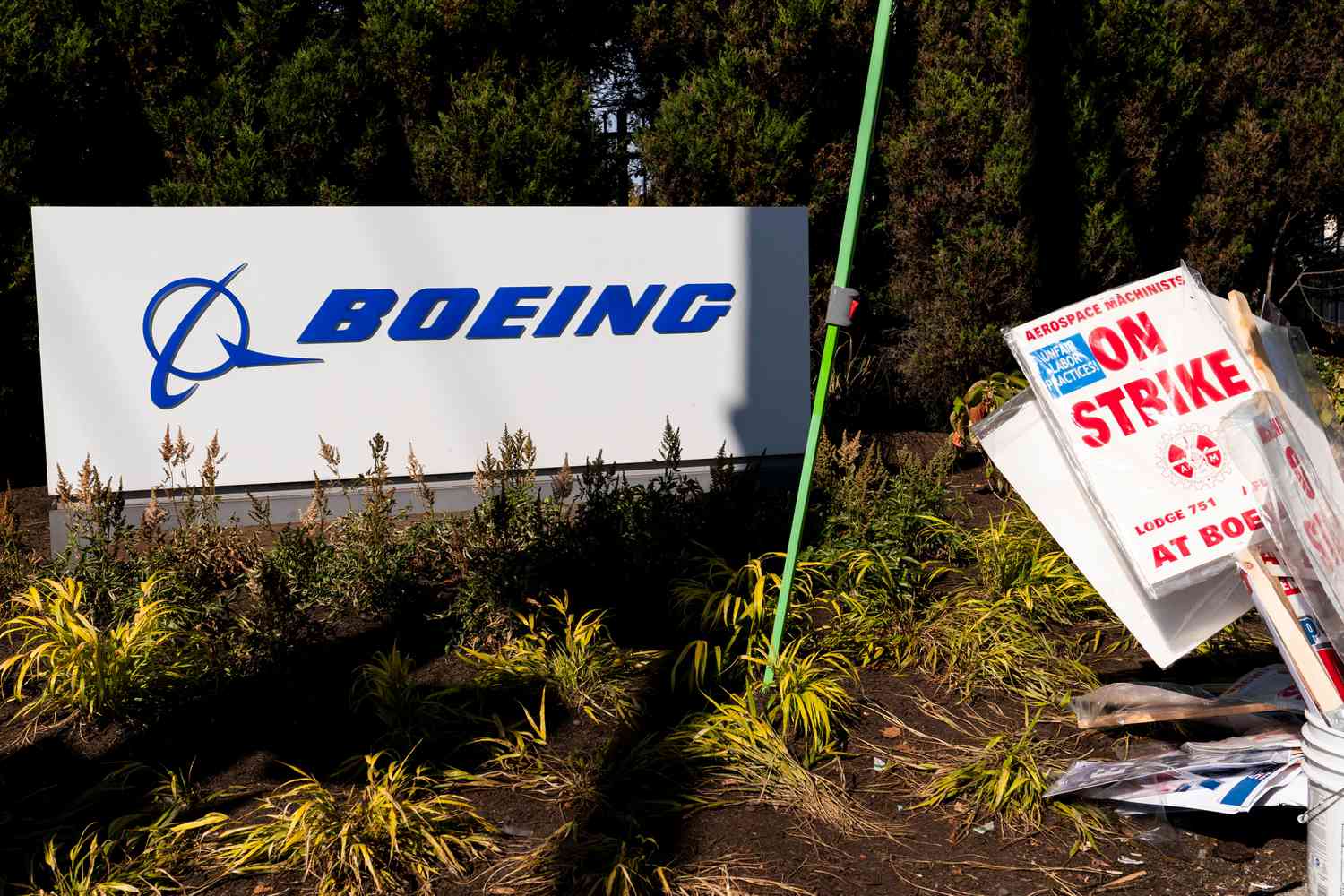 A pile of strike picket signs sit next to a Boeing sign.