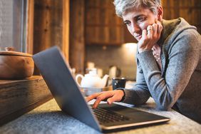 A mature person studies a laptop screen as they research Medicare Part B eligibility and costs.