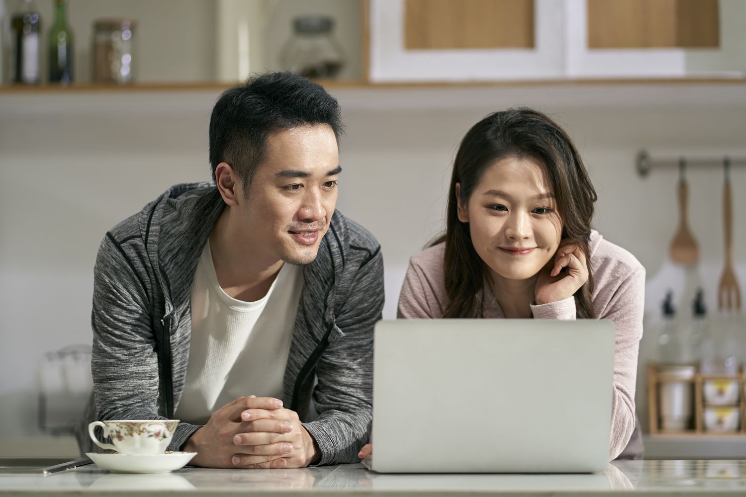 Young couple in their kitchen and looking at mortgage rates on a laptop