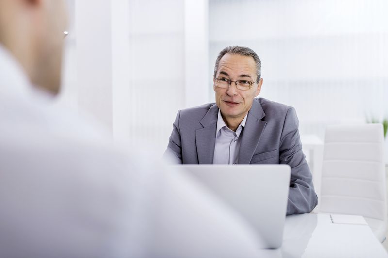 Man in a gray suit sitting on the other side of a desk