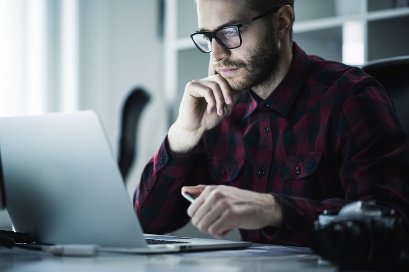 A young man looks at a laptop in a modern office.