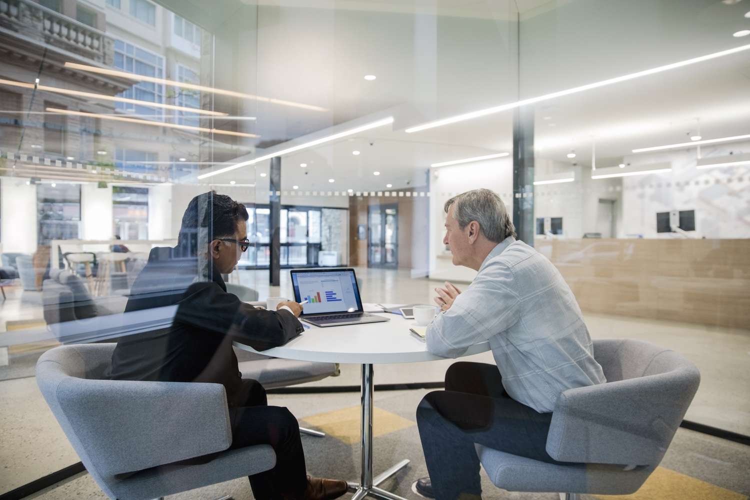 Loan manager with laptop meeting with client in bank branch office