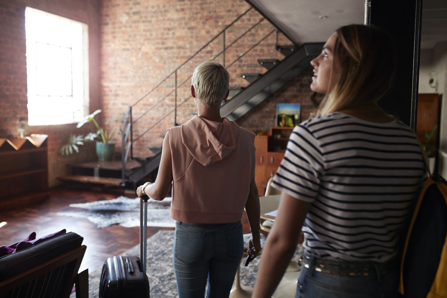 Two young woman arriving to urban rental apartment