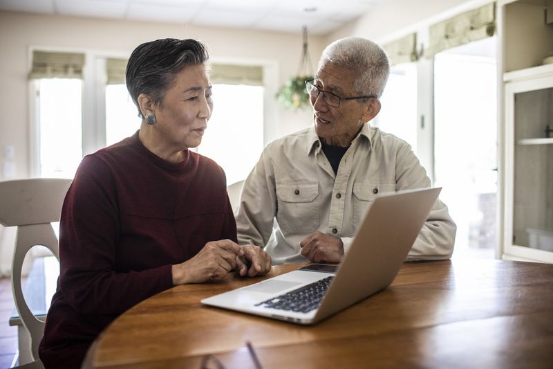 Older adult couple using laptop at home