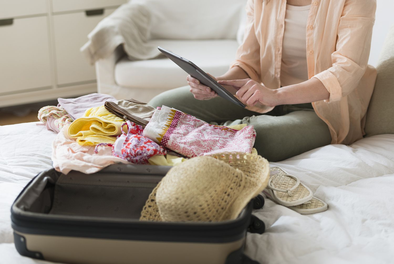 USA, New Jersey, Jersey City, Woman Using Digital Tablet While Packing Suitcase