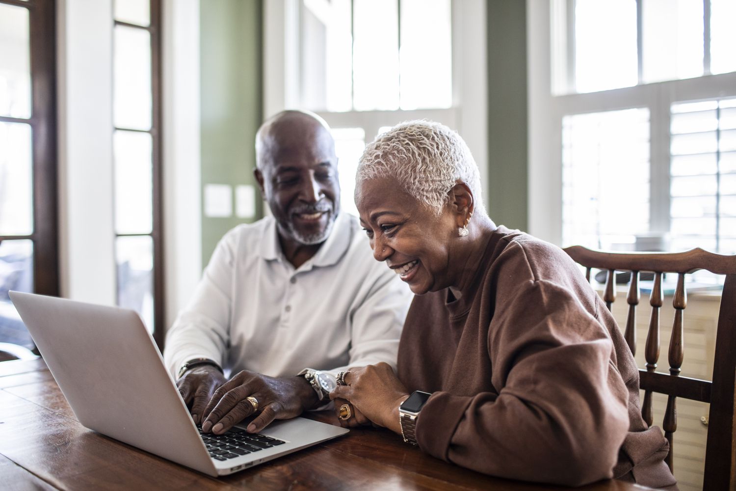 A couple looks at a laptop at home.