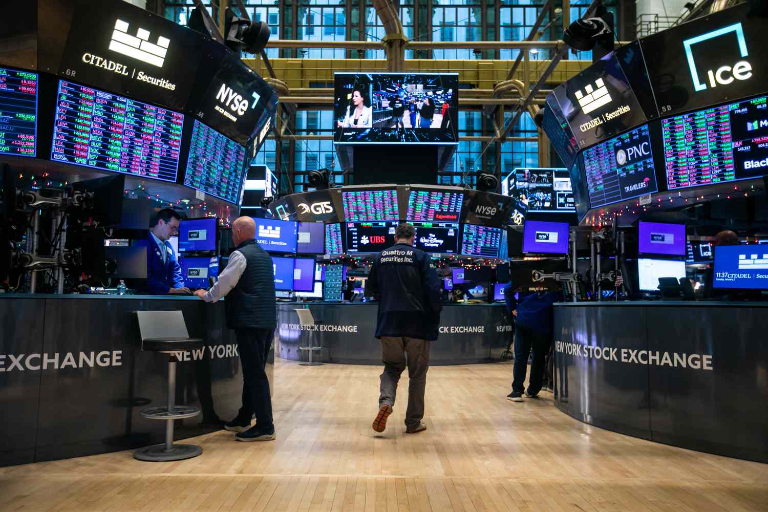 Traders walk past desks and computer screens on the floor of the New York Stock Exchange. 