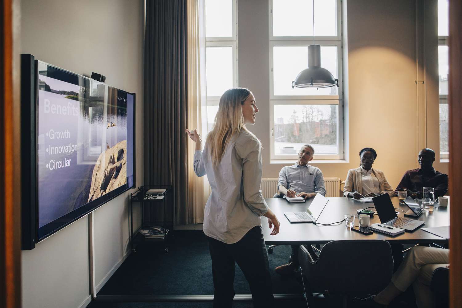 Businesswoman explaining while giving presentation to male and female colleagues in office