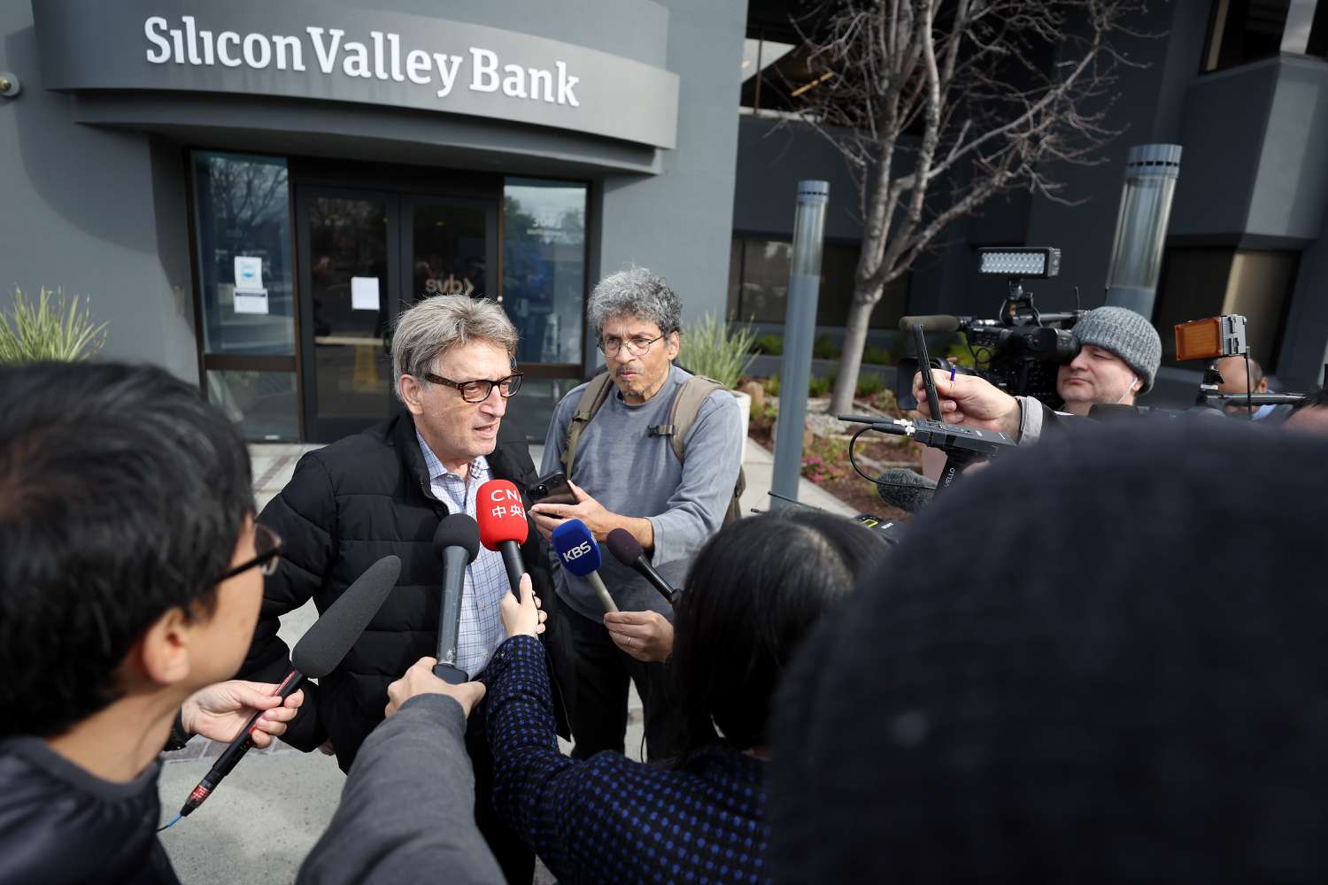 Members of the media interview a Silicon Valley Bank customer outside of the bank office on March 13, 2023 in Santa Clara, California. Days after Silicon Valley Bank collapsed, customers are lining up to try and retrieve their funds from the failed bank. The Silicon Valley Bank failure is the second largest in U.S. history.