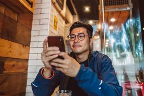A man sits at a table staring at his smartphone