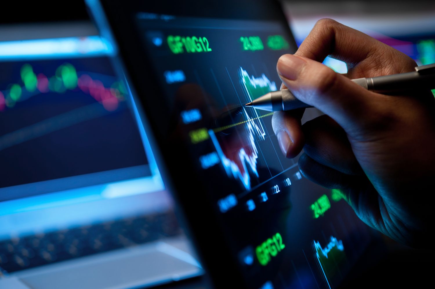 An analyst uses a ballpoint pen on a monitor screen to help them determine a trading price point. 