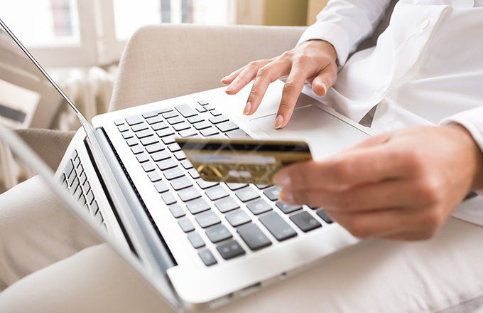Woman holding credit card, sitting with laptop in her lap