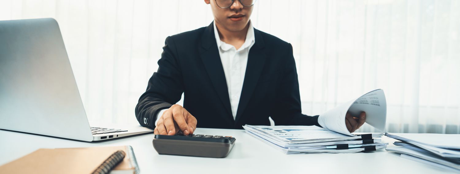 An auditor used a calculator as they compare company reported financial data to documented evidence.