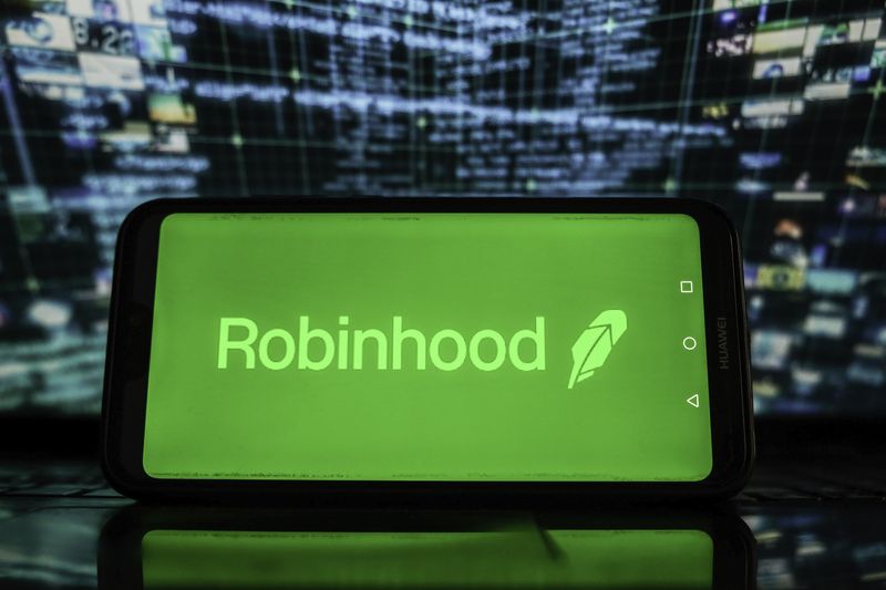 Robinhood logo on a smartphoe with stock market graphics in the background