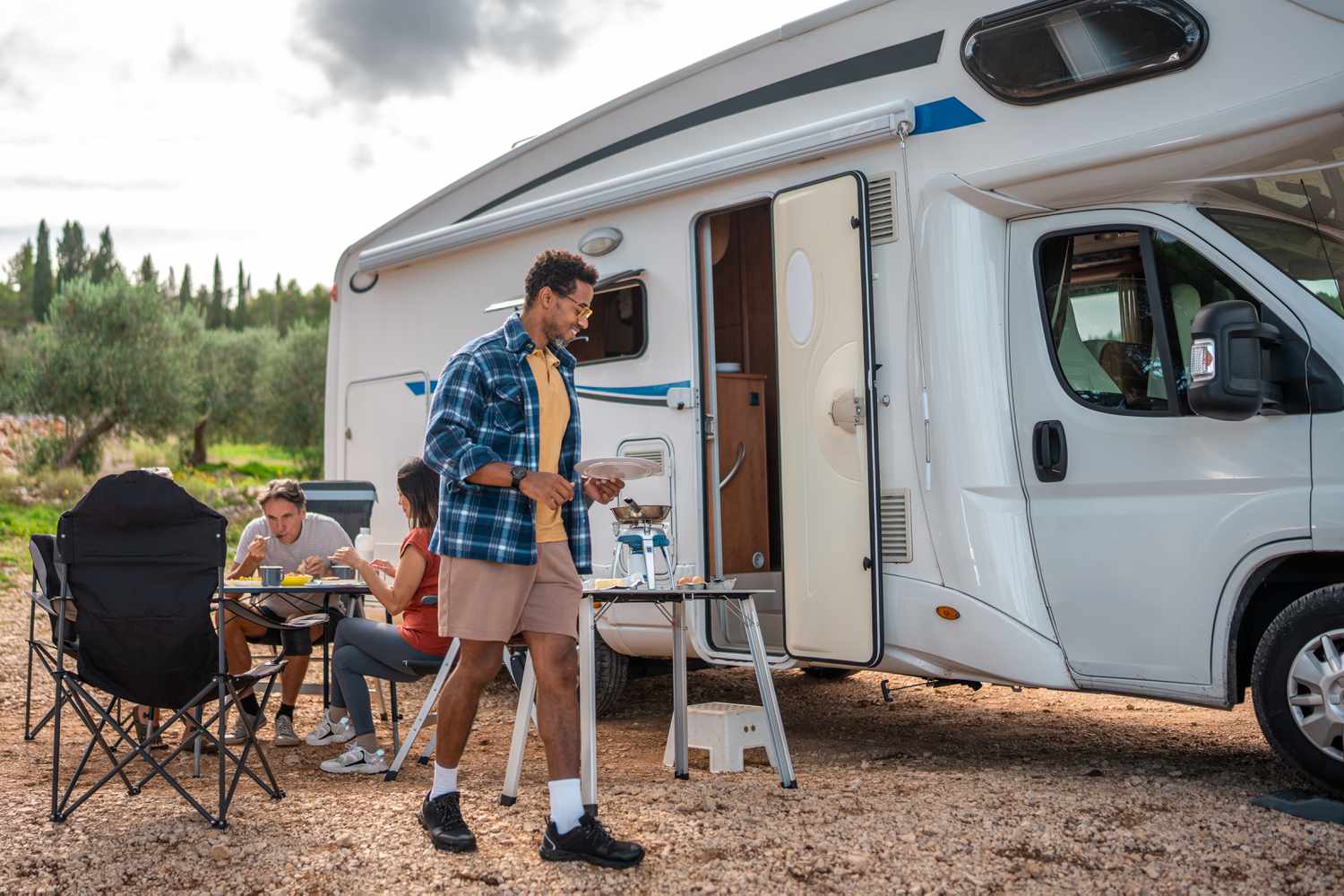 People hanging and having a picnic outside an RV on vacation.