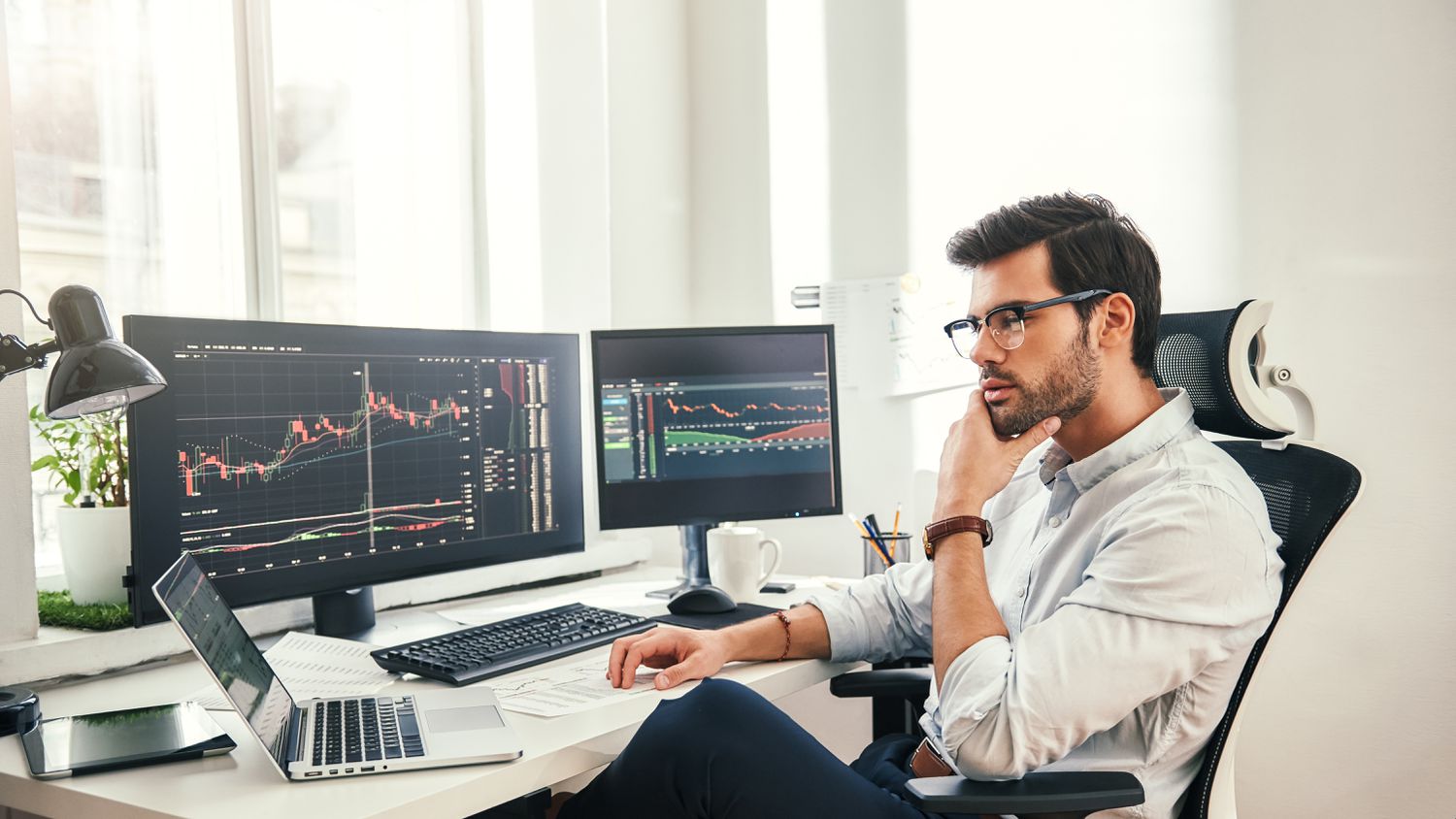 A commodities trader studies information displayed on a laptop before setting contract specifications on a forward options.