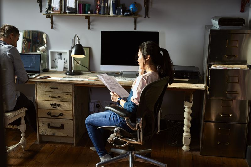 A woman looking at a statement on her chair in a home office