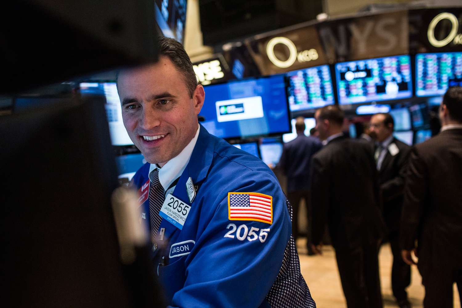 Stock trader smiling while working on the floor of the New York Stock Exchange.