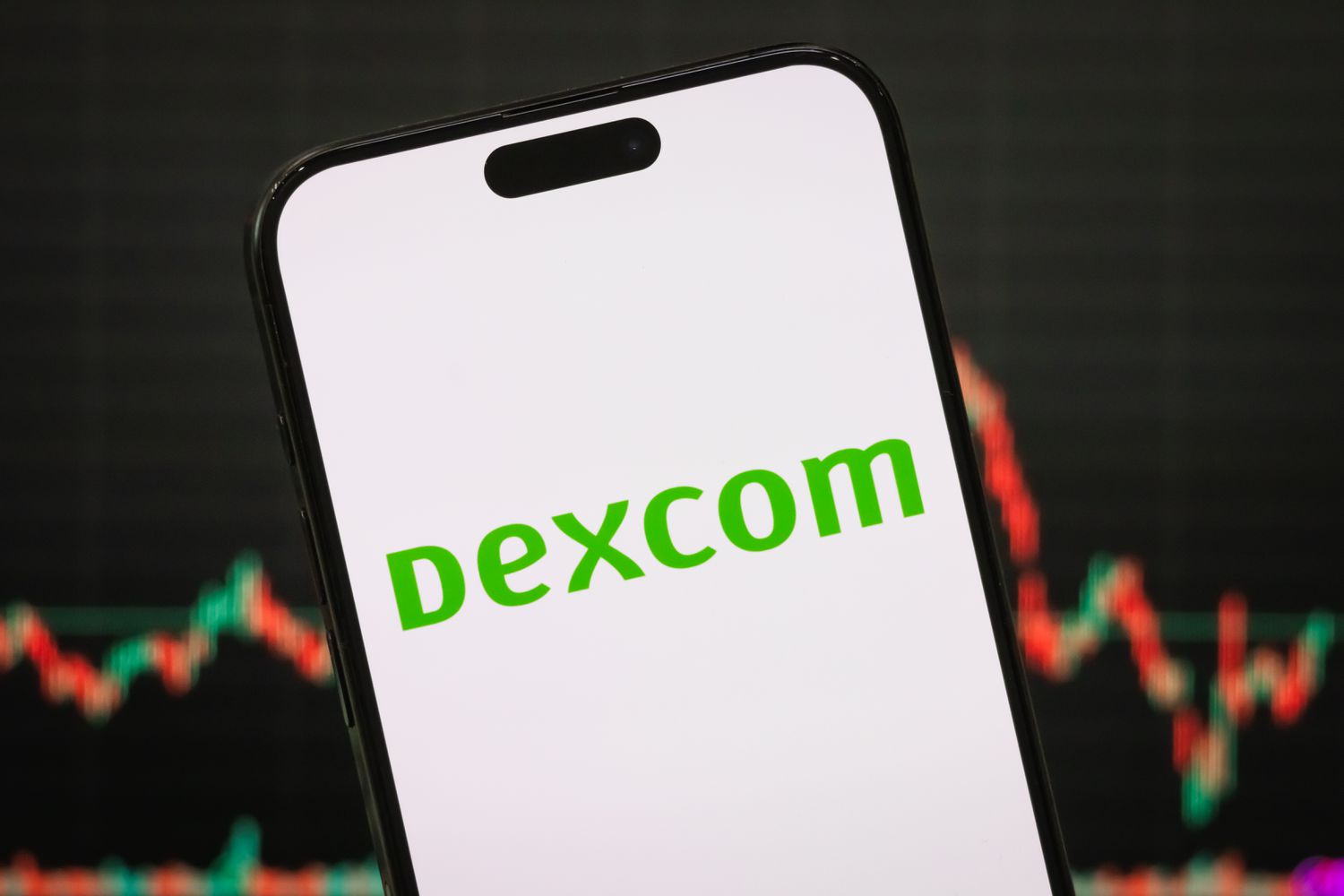The logo of DexCom Inc. displayed on a smartphone screen, with the company's stock market chart visible in the background
