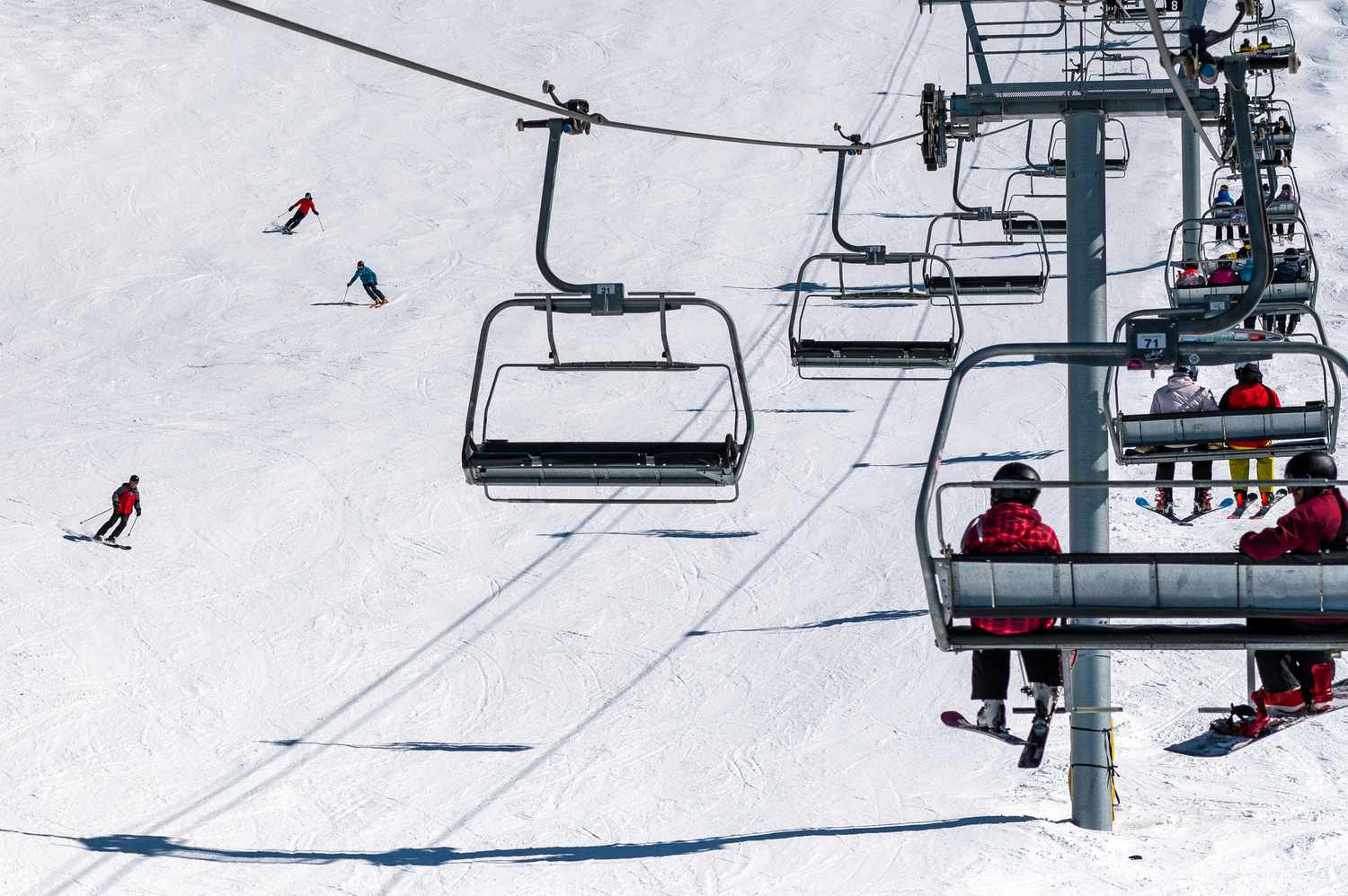 Skiers pass under a chairlift at the Whistler Blackcomb ski resort on Whistler Mountain, British Columbia, Canada