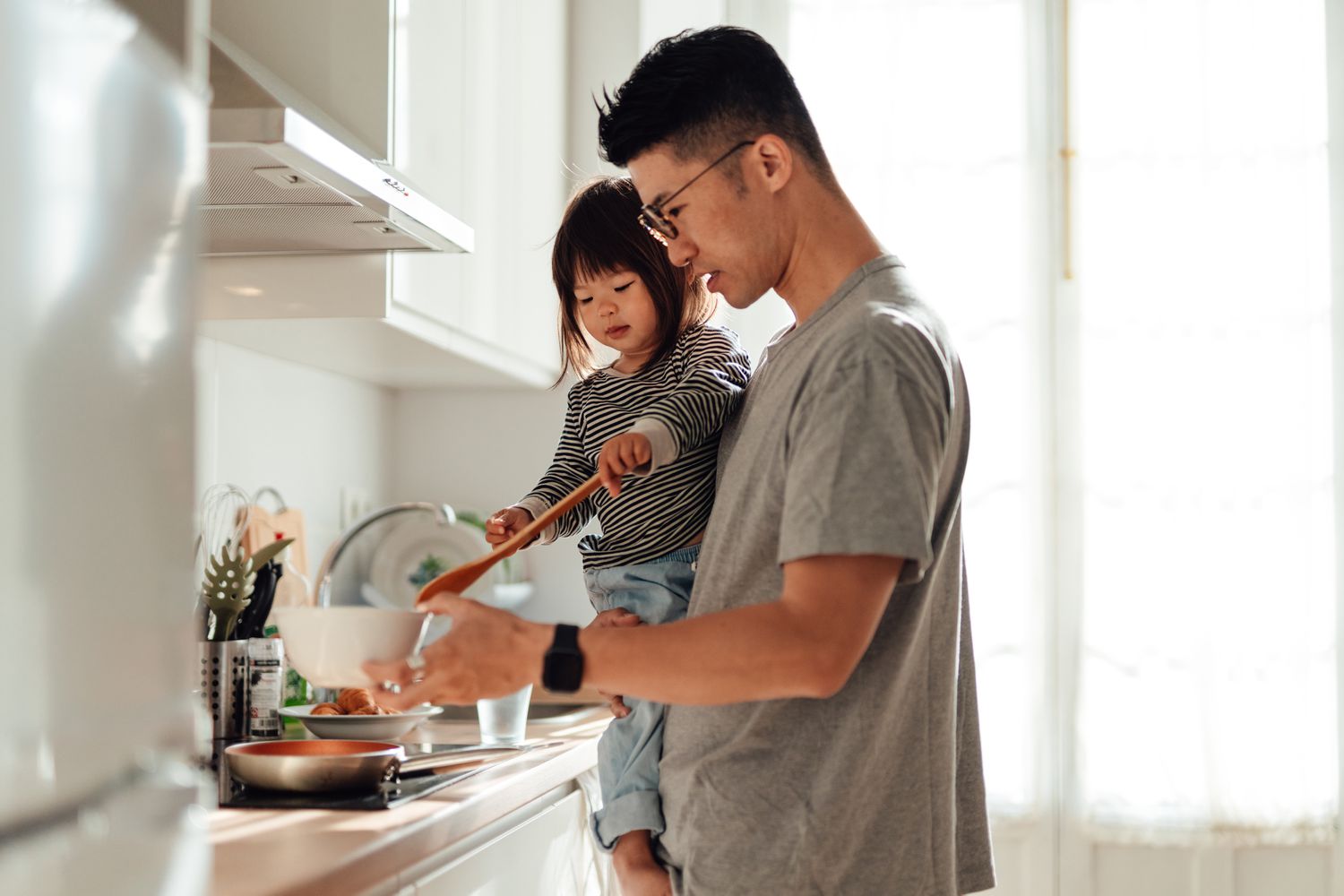 A parent holds a child in a home kitchen after applying for a DPA loan.