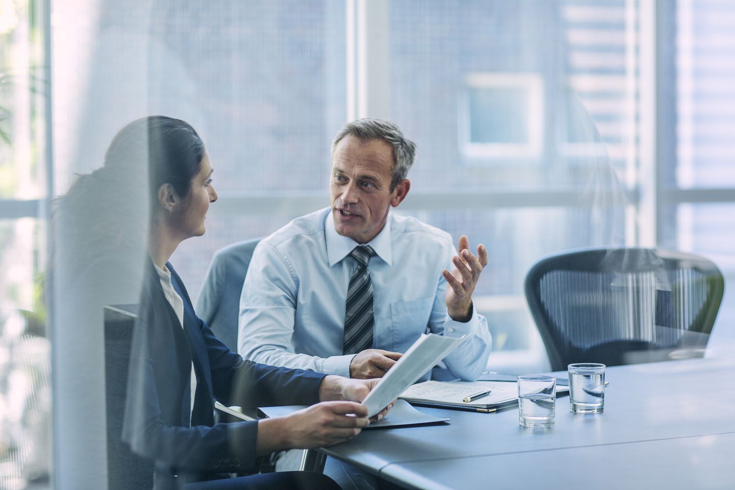 Two business professionals work at a conference table to compile financial information for the company prospectus.