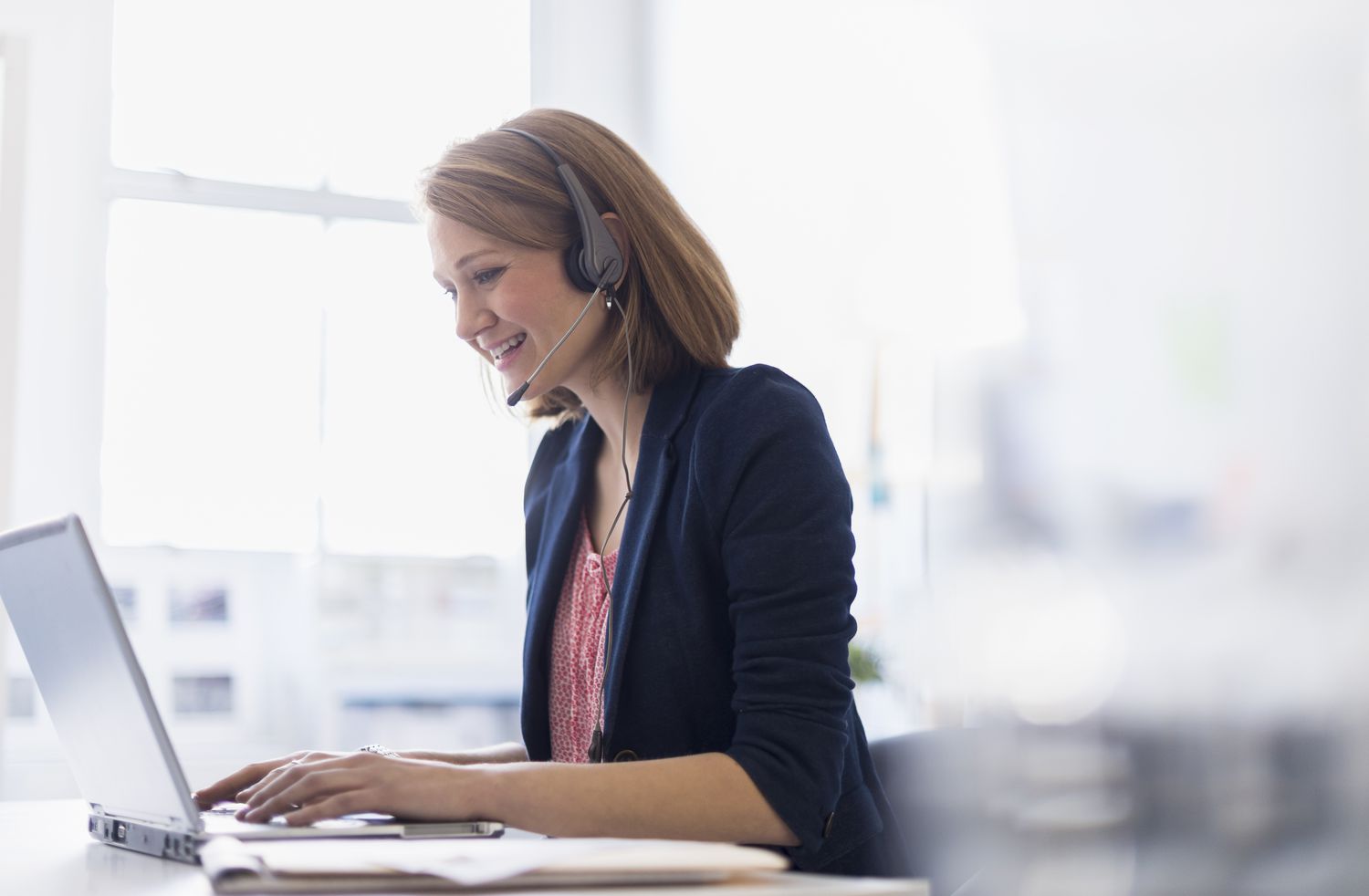 USA, New Jersey, Jersey City, Young office worker talking on headset and typing