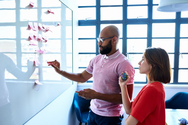 Co-workers planning with notes on whiteboard in office space