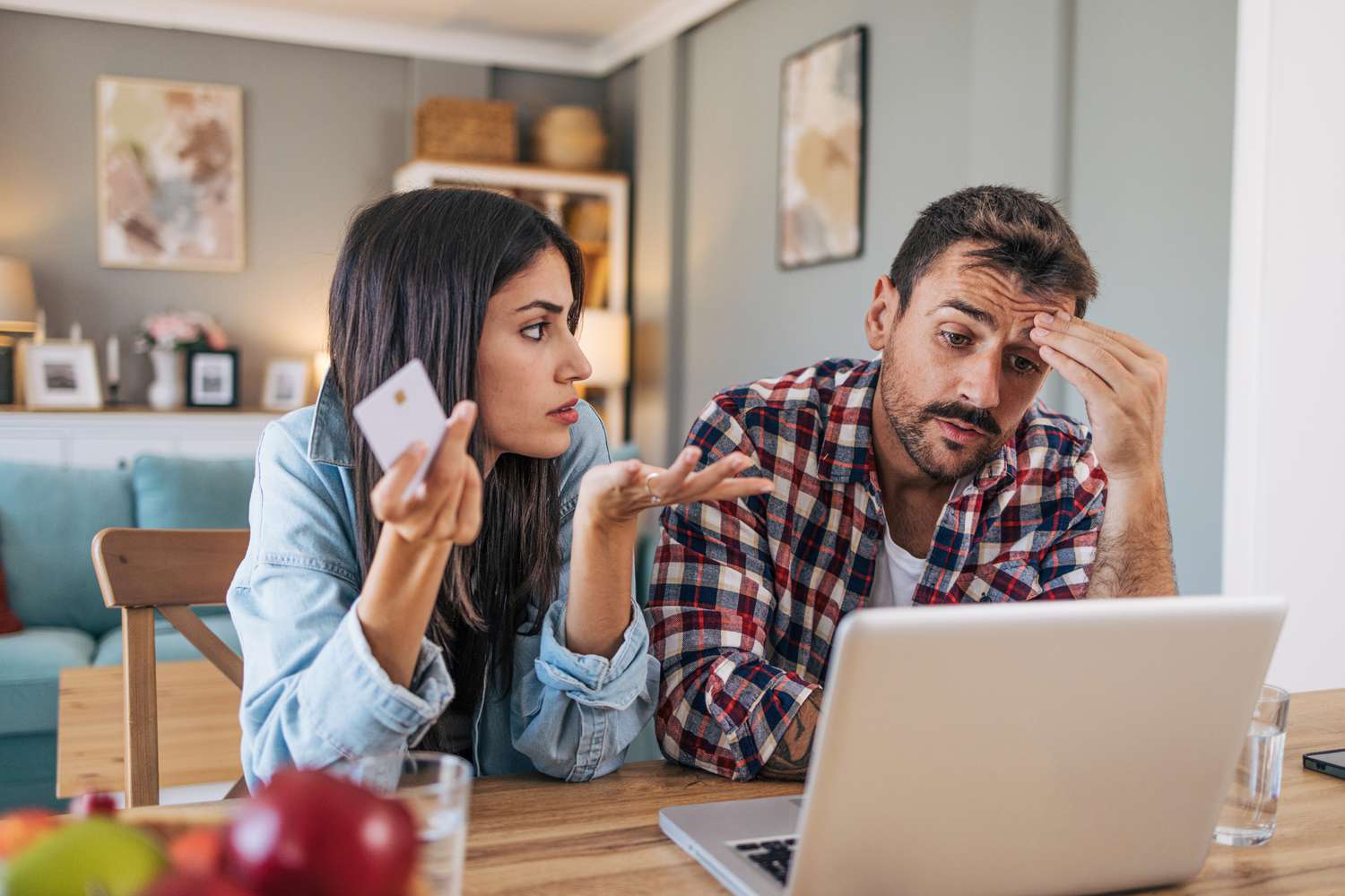 A concerned couple discussing while using a laptop at home