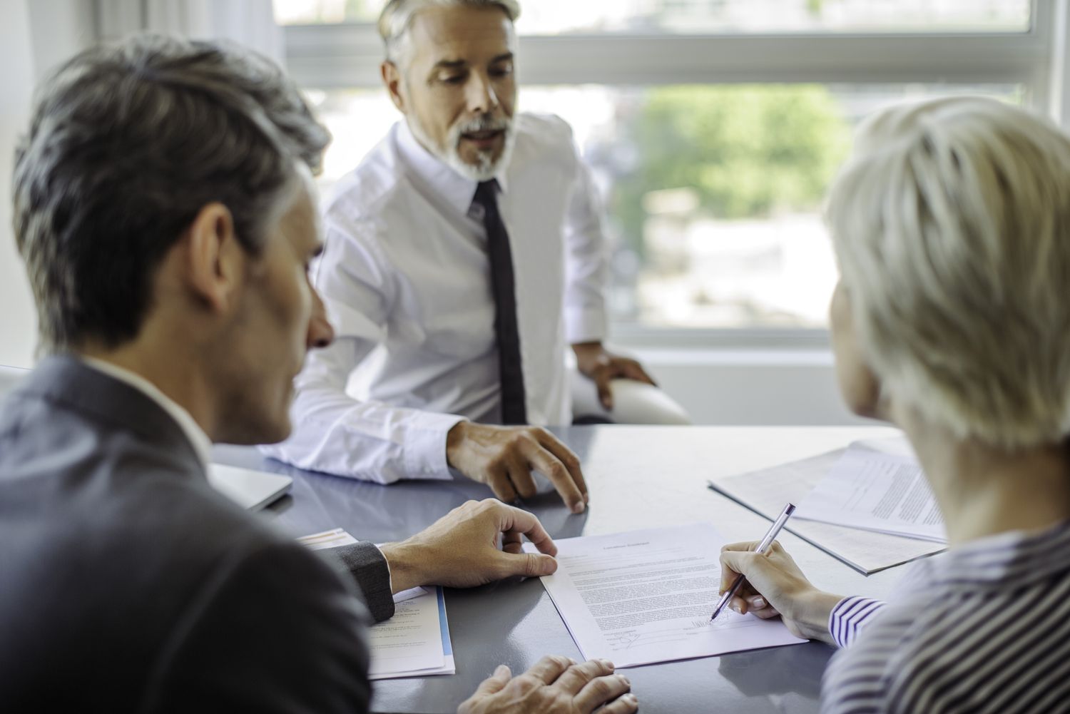 An insurance agent sits across a desk from a couple and explains the length of time, or term, that the policy will cover.