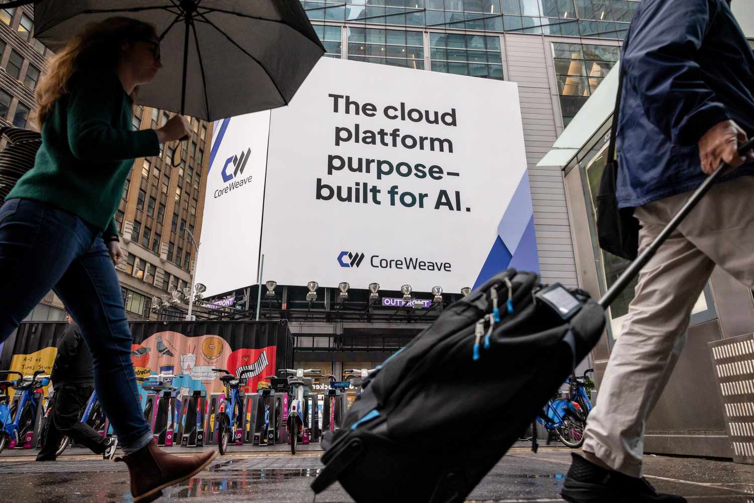 Street view with pedestrians passing under an advertisement for CoreWeave, describing it as an AI-purpose cloud platform