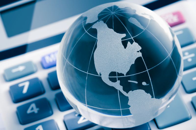 A calculator and a mini crystal globe on stock charts.