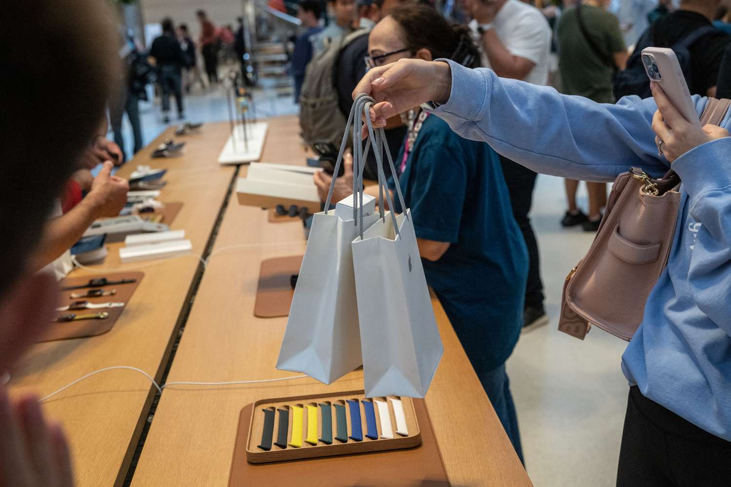 A customer photographs shopping bags during the first day of in-store sales of Apple's latest products at Apple's Fifth Avenue store in New York, US, on Friday, Sept. 20, 2024.