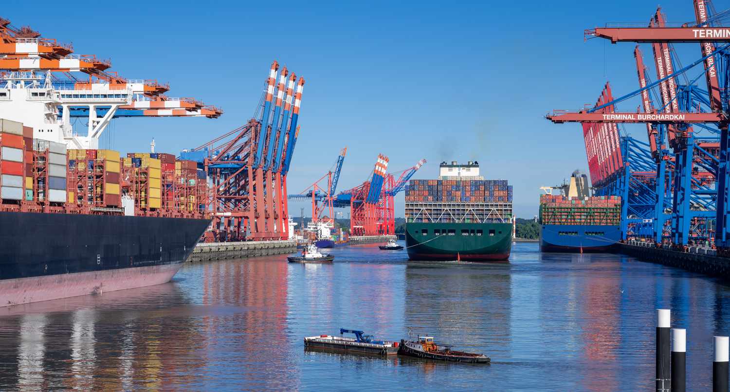 Three container ships load export cargo at the harbor of Hamburg, Germany.