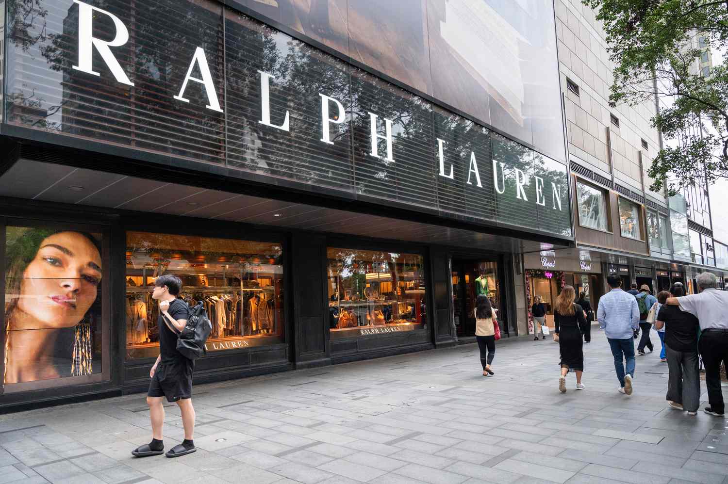 The exterior of a Ralph Lauren store is seen with people walking by outside.