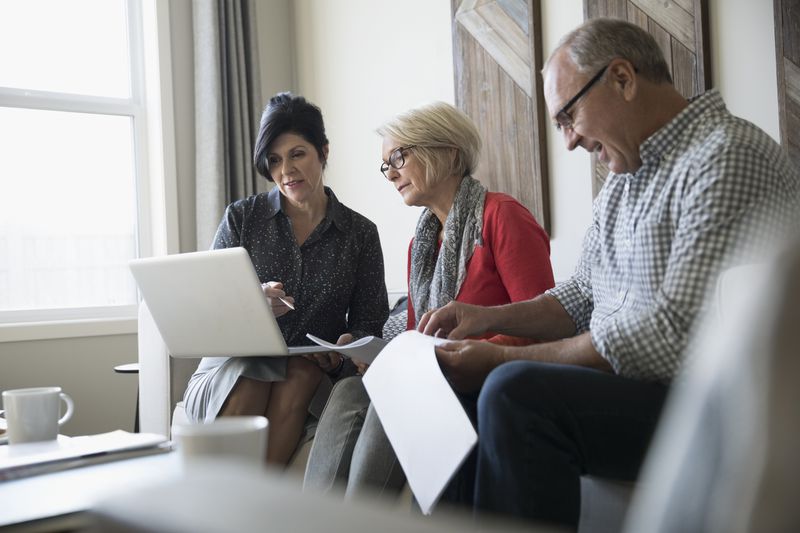 Financial advisor with laptop meeting with senior couple in living room