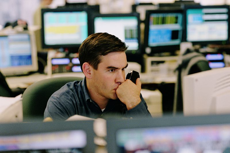 Broker Watching Stock and Holding Phone