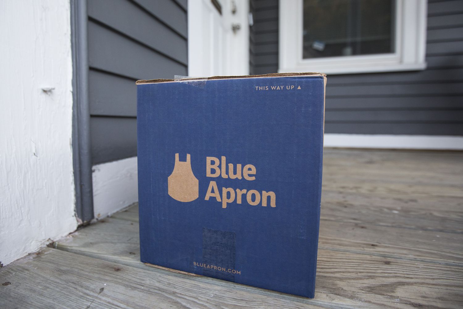 Blue Apron box sits on the porch of a house.